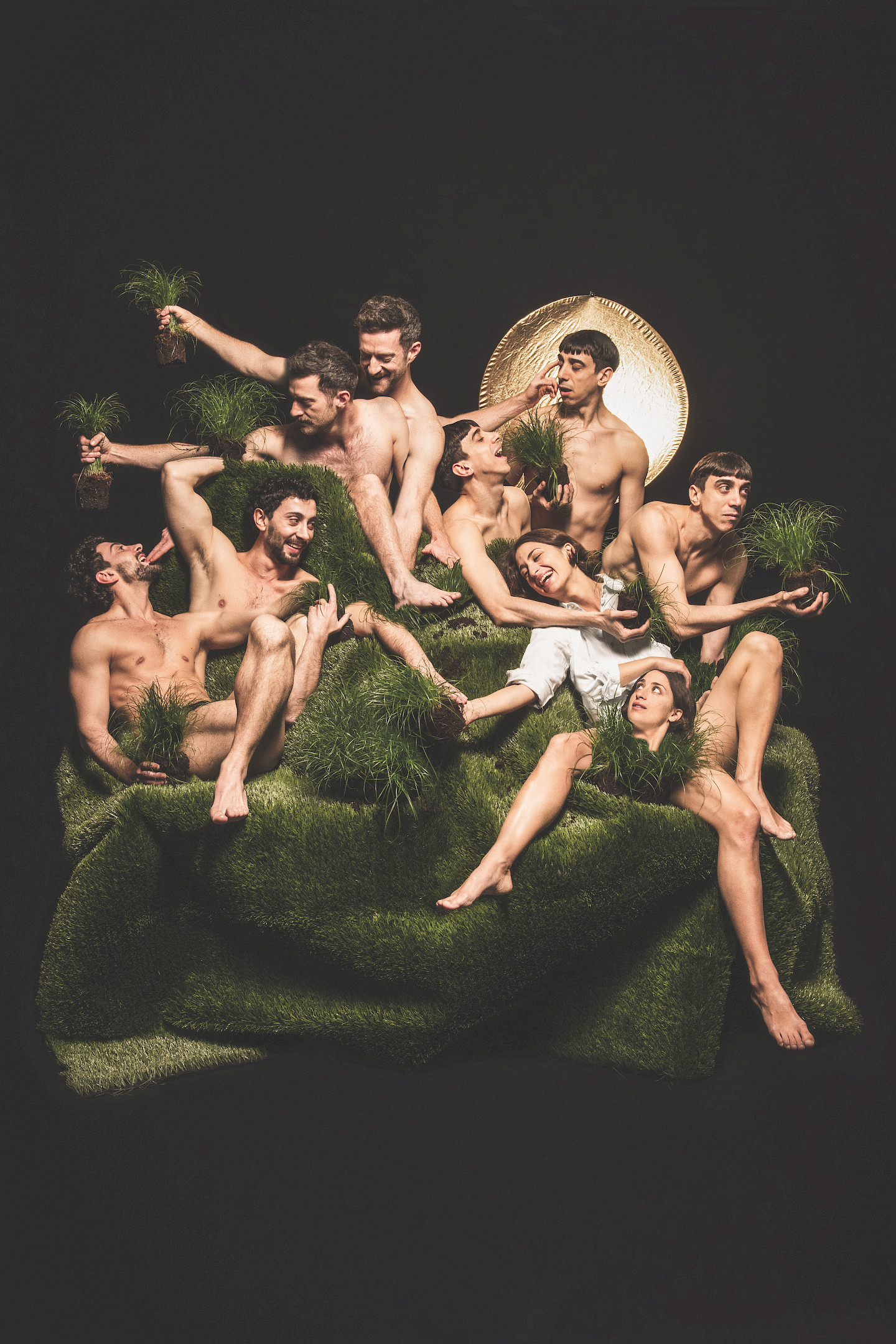 A group of almost undressed dancers on a sheet of green artificial grass