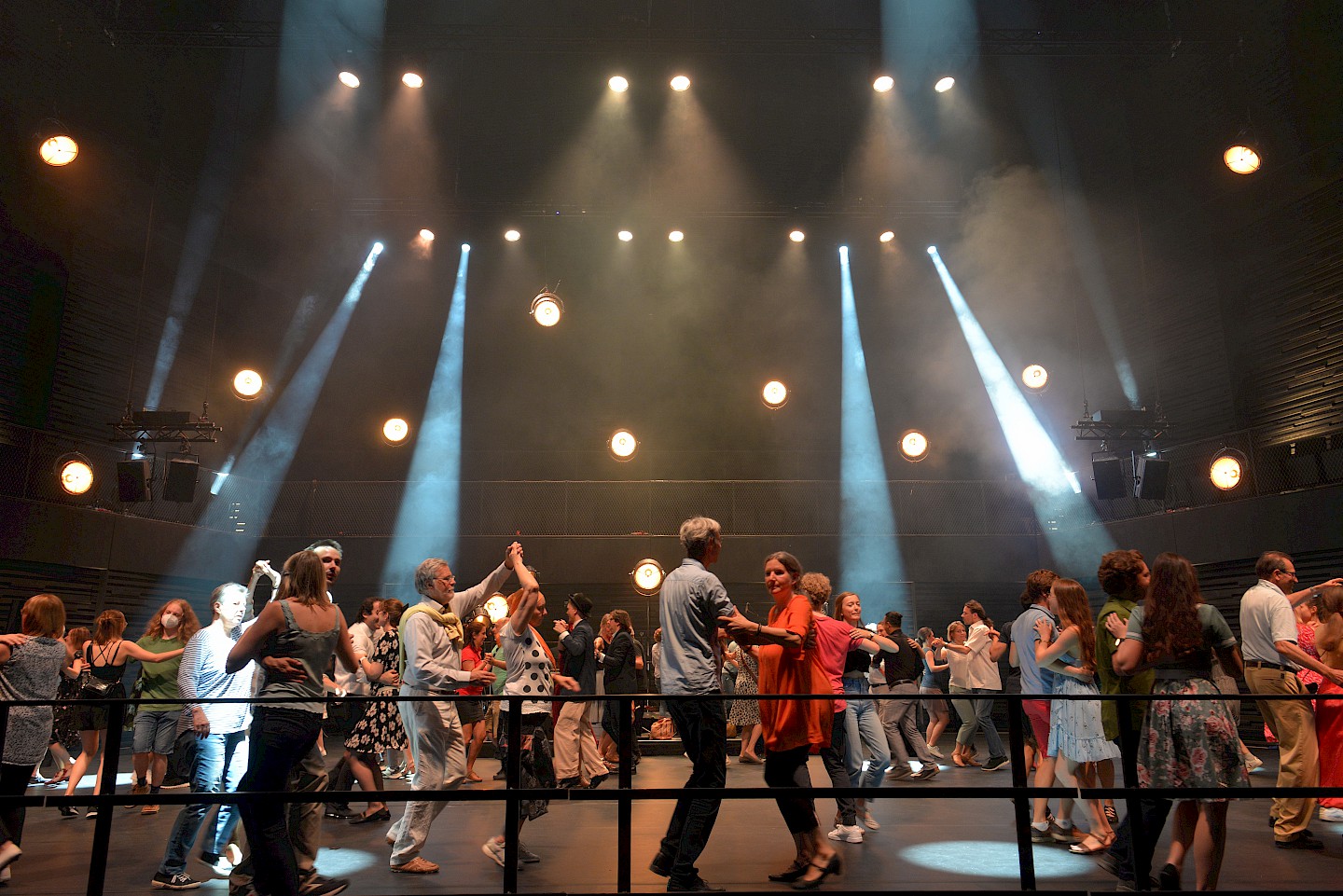 Menschen tanzen im Scheinwerferlicht auf der Bühne des Isarphilharmonie.