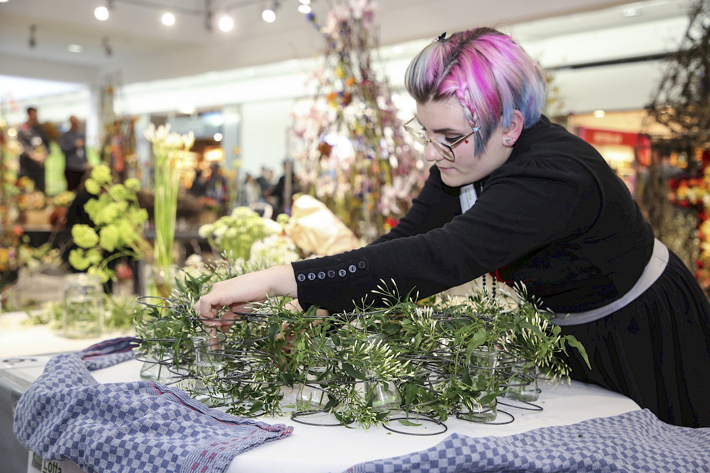 A florist designs a wreath of flower branches and flowers.