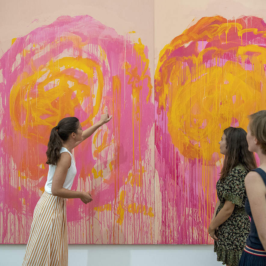 Drei Personen stehen vor einer Malerei mit abstrakten Blumen in Pink und Orange