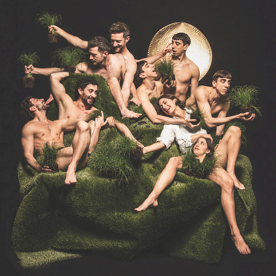 Eine Gruppe nahezu unbekleideter Tänzer:innen auf einem Tuch aus grünem Kunstrasen